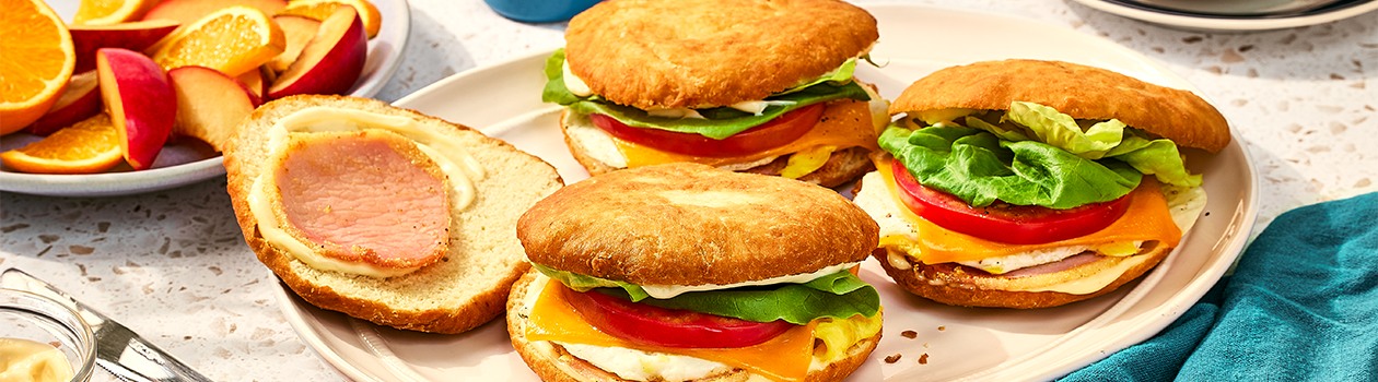 Three bannock breakfast sandwiches and a bannock bun on a white plate.
