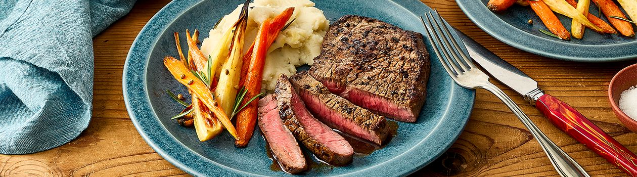Sliced bison sirloin steak with mashed potatoes and roasted carrots.