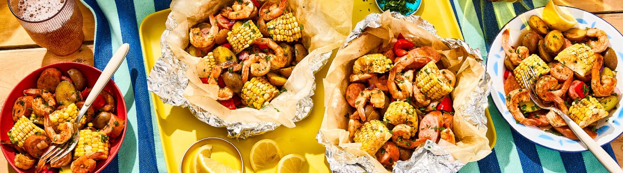 Overhead shot of shrimp boil aluminum packets with shrimp, corn, sausage and potato.