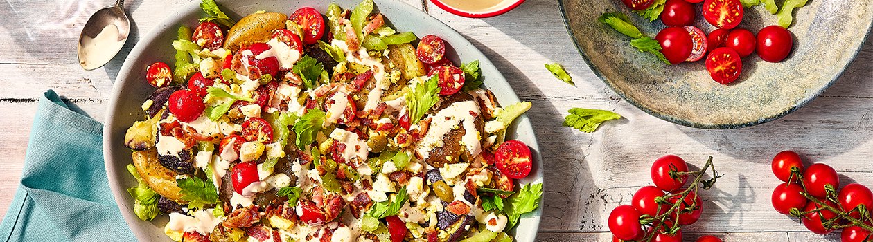 Overhead shot of the Canadian-Caesar Smashed potatoes in a platter with cherry tomatoes on the side.