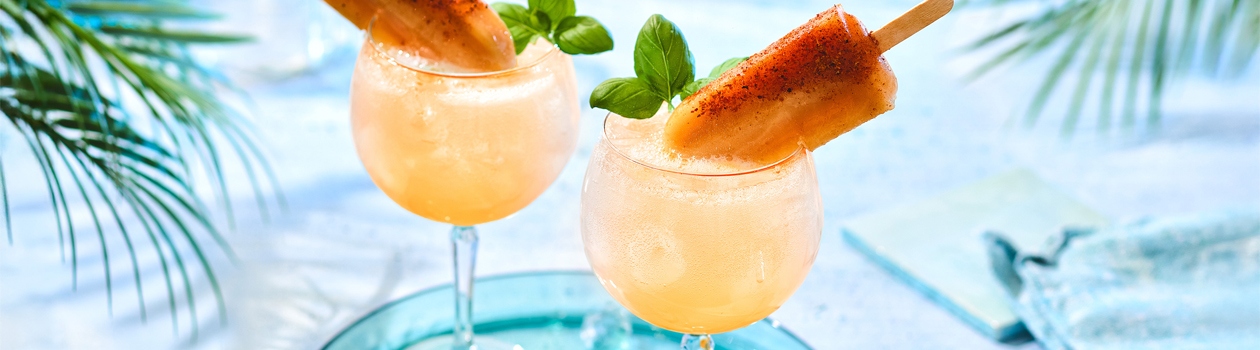 Two guava popsicle fizz cocktails on marble tabletop