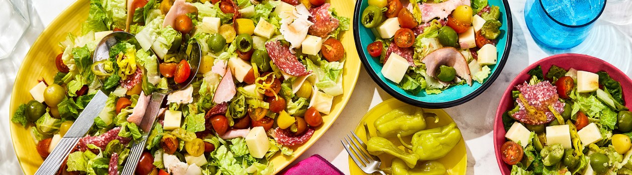 Italian grinder salad in a platter and 2 small bowls filled with salad beside it.
