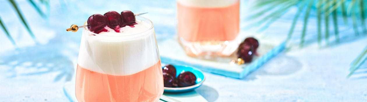 Two cherry sours in glasses garnished with 3 cherries.