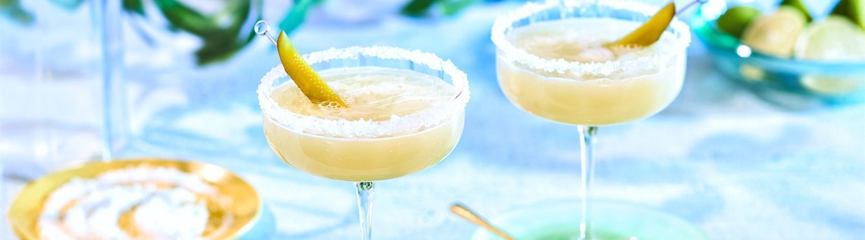 Pickle margarita on marble table top garnished with pickle slice