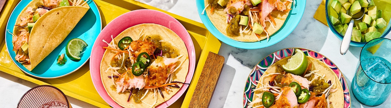 Overhead shot of salmon tacos topped with jalapeno, chili salsa, and slaw.