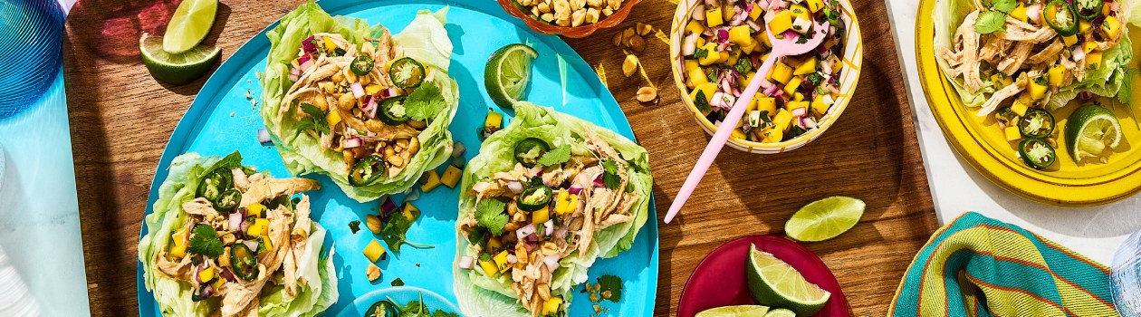 3 Thai mango chicken lettuce wraps on a plate with mango salsa in a bowl to the side.